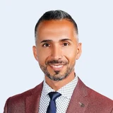 Birol Isik, Gründer der SNF Academy, Porträt im bordeauxroten Sakko mit dunkler Krawatte